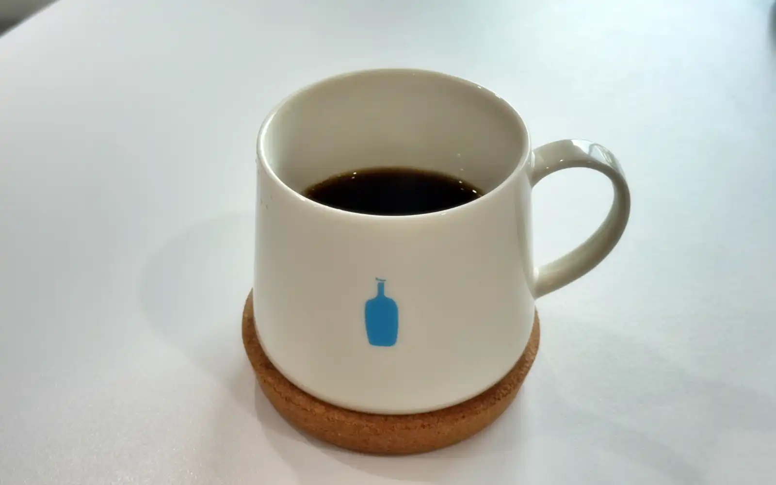 테이블 위에 올려진 커피가 들어있는 블루보틀 머그컵 사진
