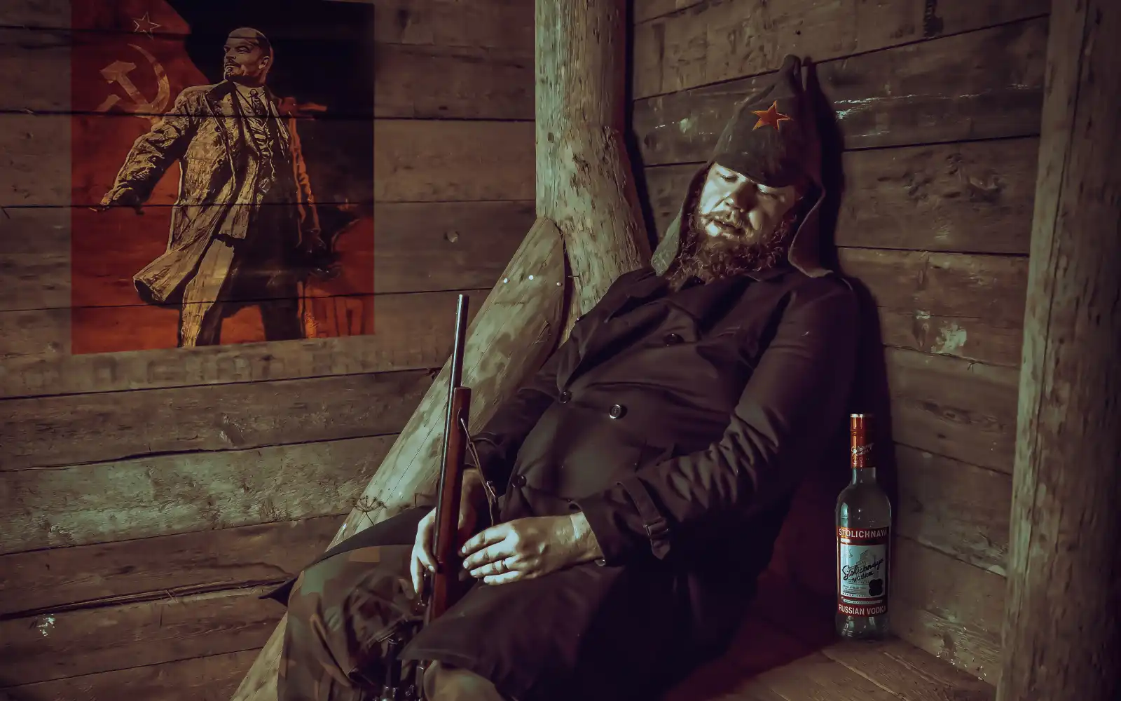 급성 알콜중독, 남성이 나무로된 집에서 총을 들고 의자에 앉아 있으며 눈을 감고 있다. 옆에는 술 병이 보이는 사진